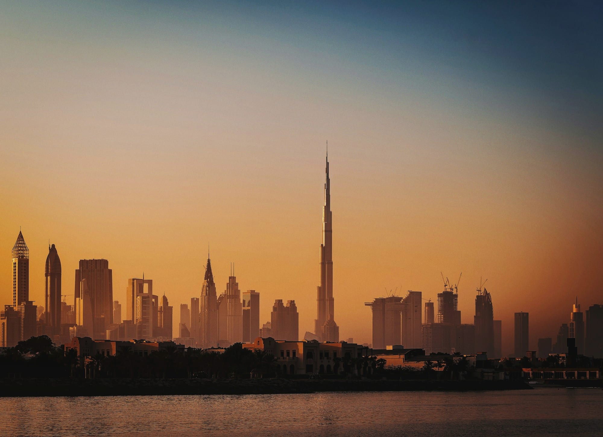 The Dubai skyline across the water at sunset.