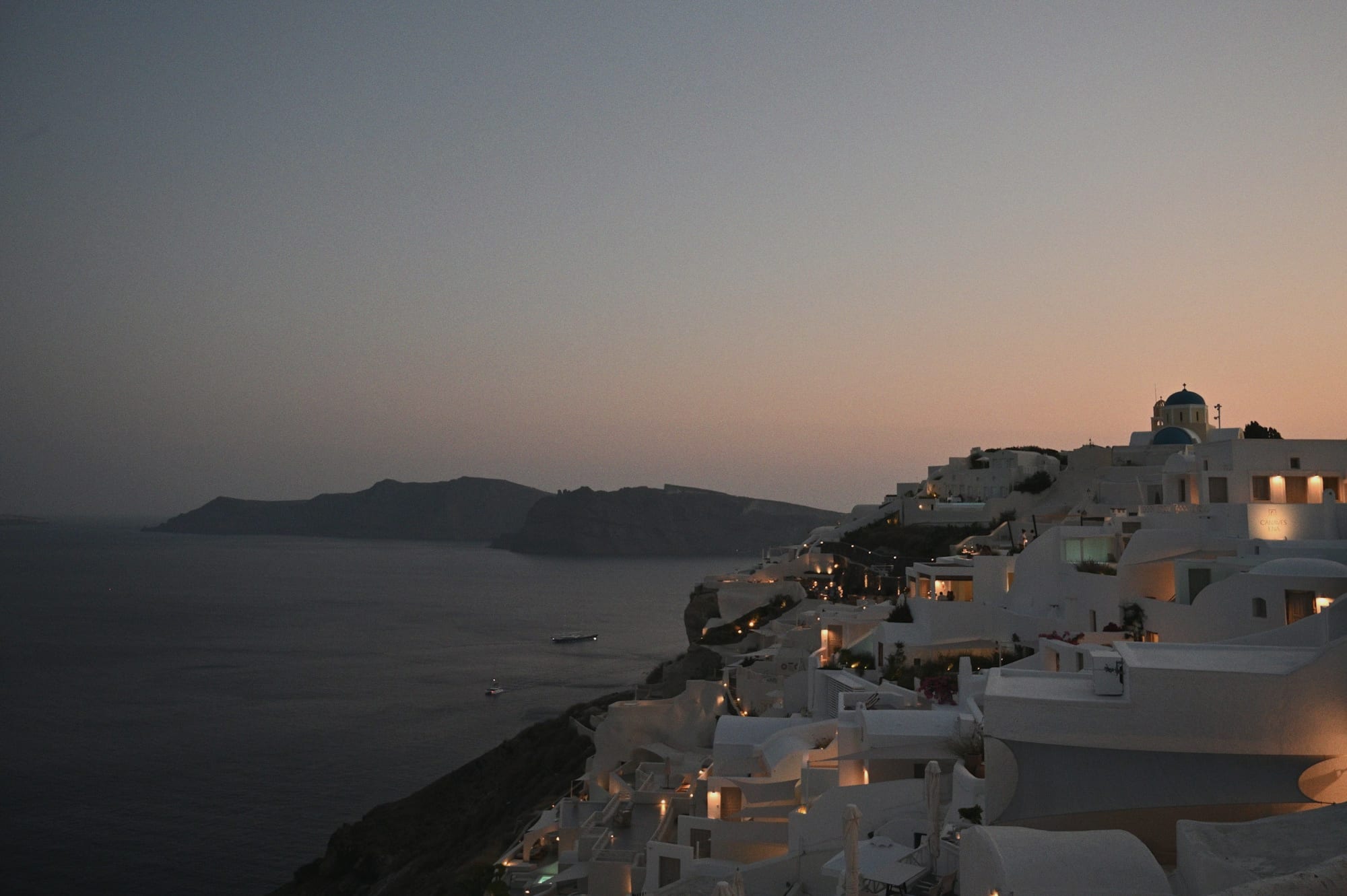 White cliffside houses above the Santorini caldera at dusk.