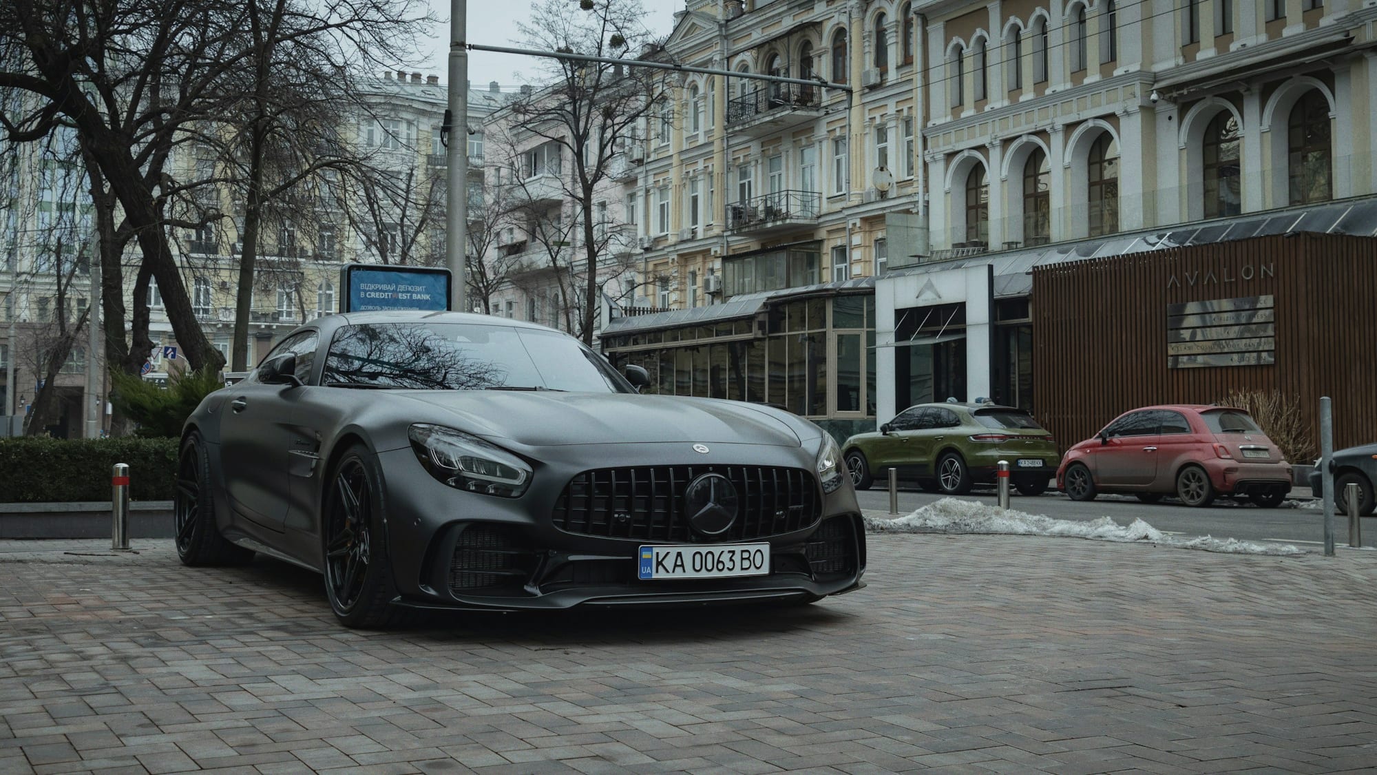 A dark saloon car waiting on a quiet city street at night.
